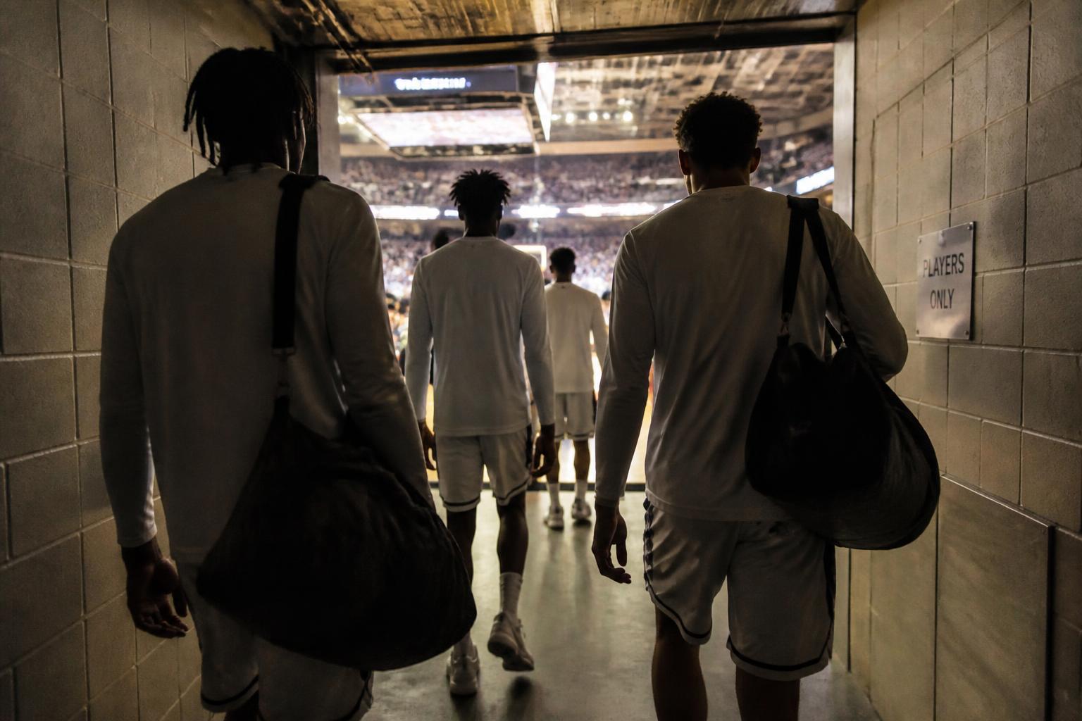 Basketball players walking through the arena tunnel toward the court